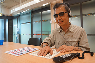 失明人士李健在使用凸紋觸感圖和口述影像聲帶